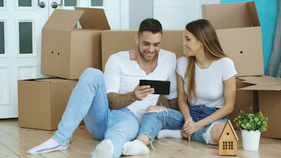 Couple looking at tablet surrounded by moving boxes