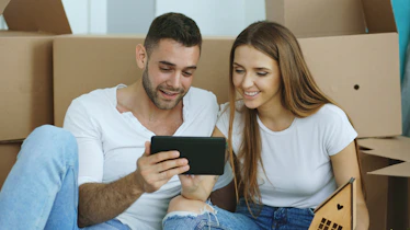 Couple looking at tablet surrounded by moving boxes
