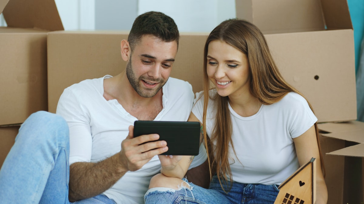 Couple looking at tablet surrounded by moving boxes