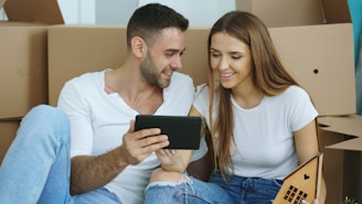 Couple looking at tablet surrounded by moving boxes