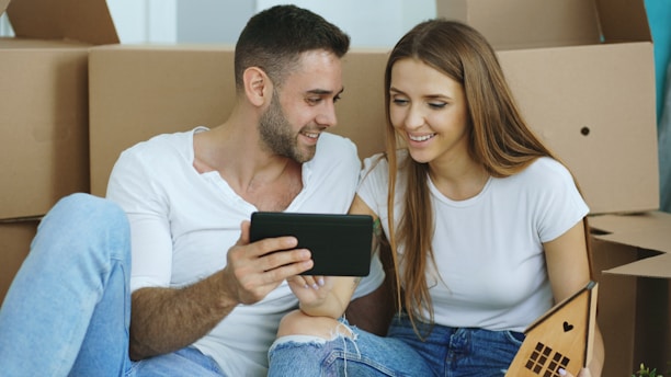 Couple looking at tablet surrounded by moving boxes