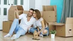 Couple sitting on floor surrounded by moving boxes