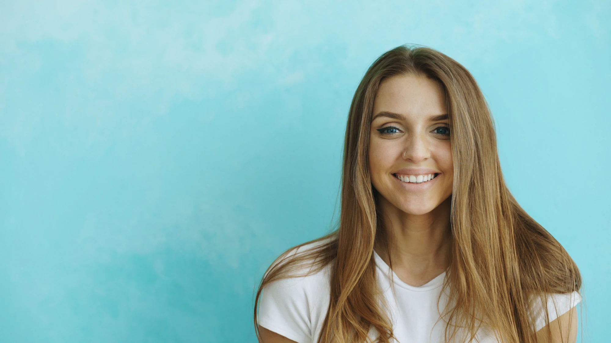 Young woman smiling against a blue textured wall
