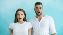 Couple with shocked expressions against blue background