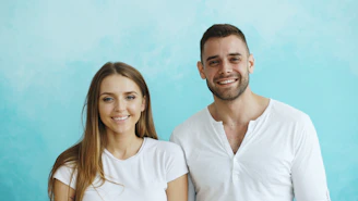 Smiling couple in white shirts against blue background