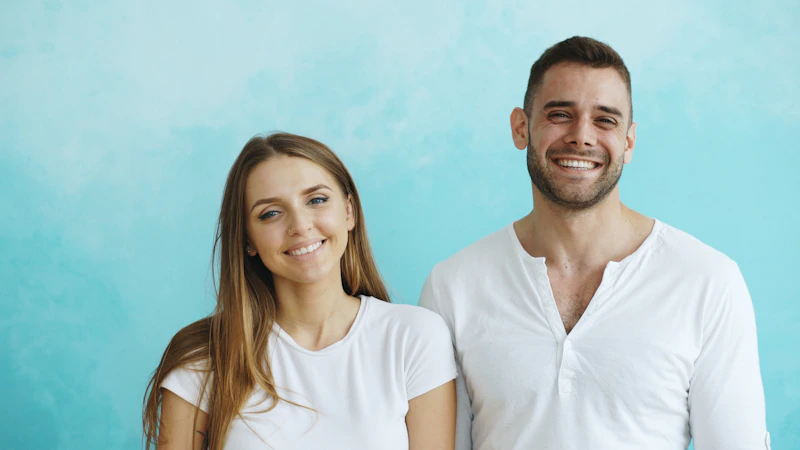 smiling dating couple in white t-shirts against a blue wall