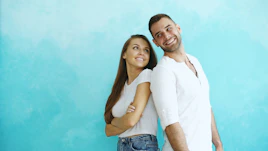 Couple standing back to back against blue wall