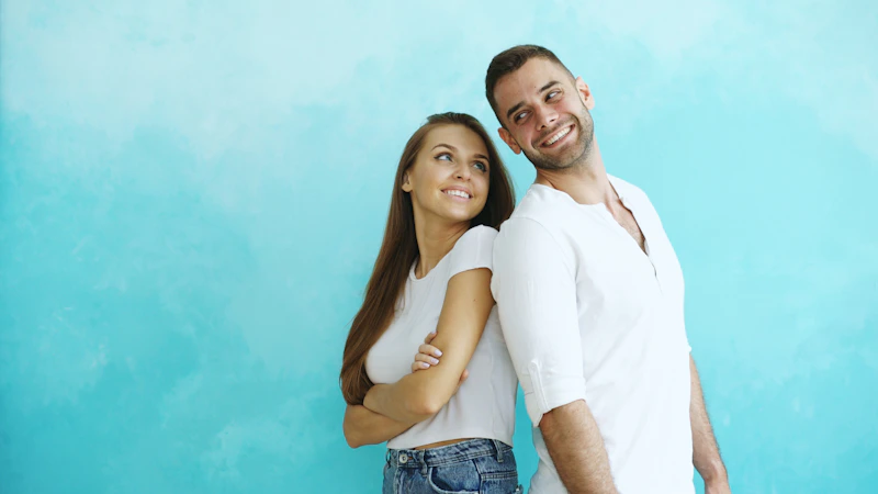 couple standing back to back against a blue wall
