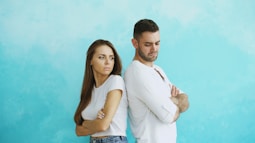 Couple standing back to back with arms crossed