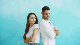 Couple standing back to back with arms crossed