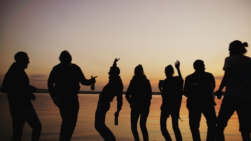 Silhouettes of people dancing against a sunset sky.