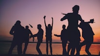 Silhouetted friends celebrating on a beach at sunset