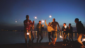 Group of friends celebrating with sparklers at night.