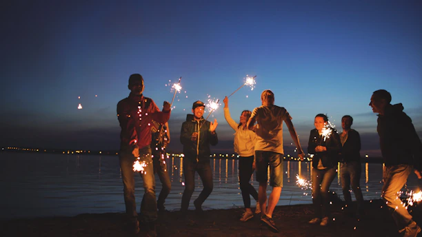 Group of friends celebrating with sparklers at night.