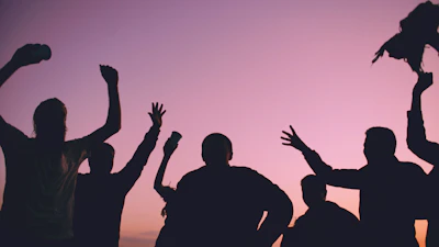 Silhouettes of people celebrating against a purple sky