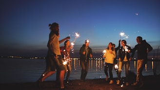 Friends celebrating with sparklers by the water at night