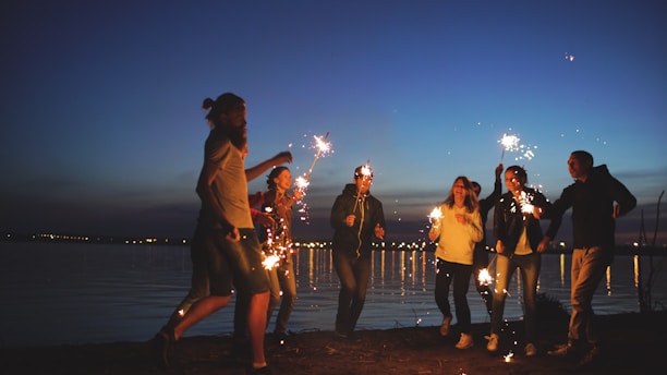 Friends celebrating with sparklers by the water at night