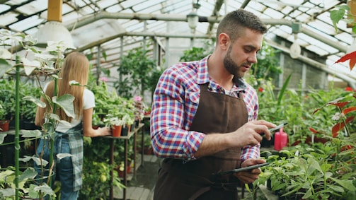 Man and girl tending plants in a greenhouse.