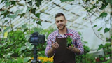 Man holding a potted plant in a greenhouse.