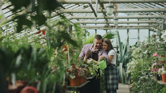 Father and daughter watering plants in greenhouse