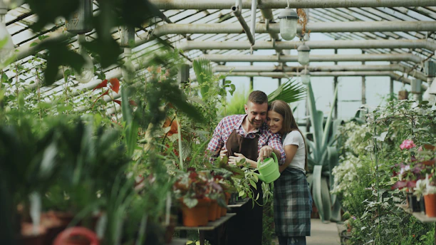Father and daughter watering plants in greenhouse