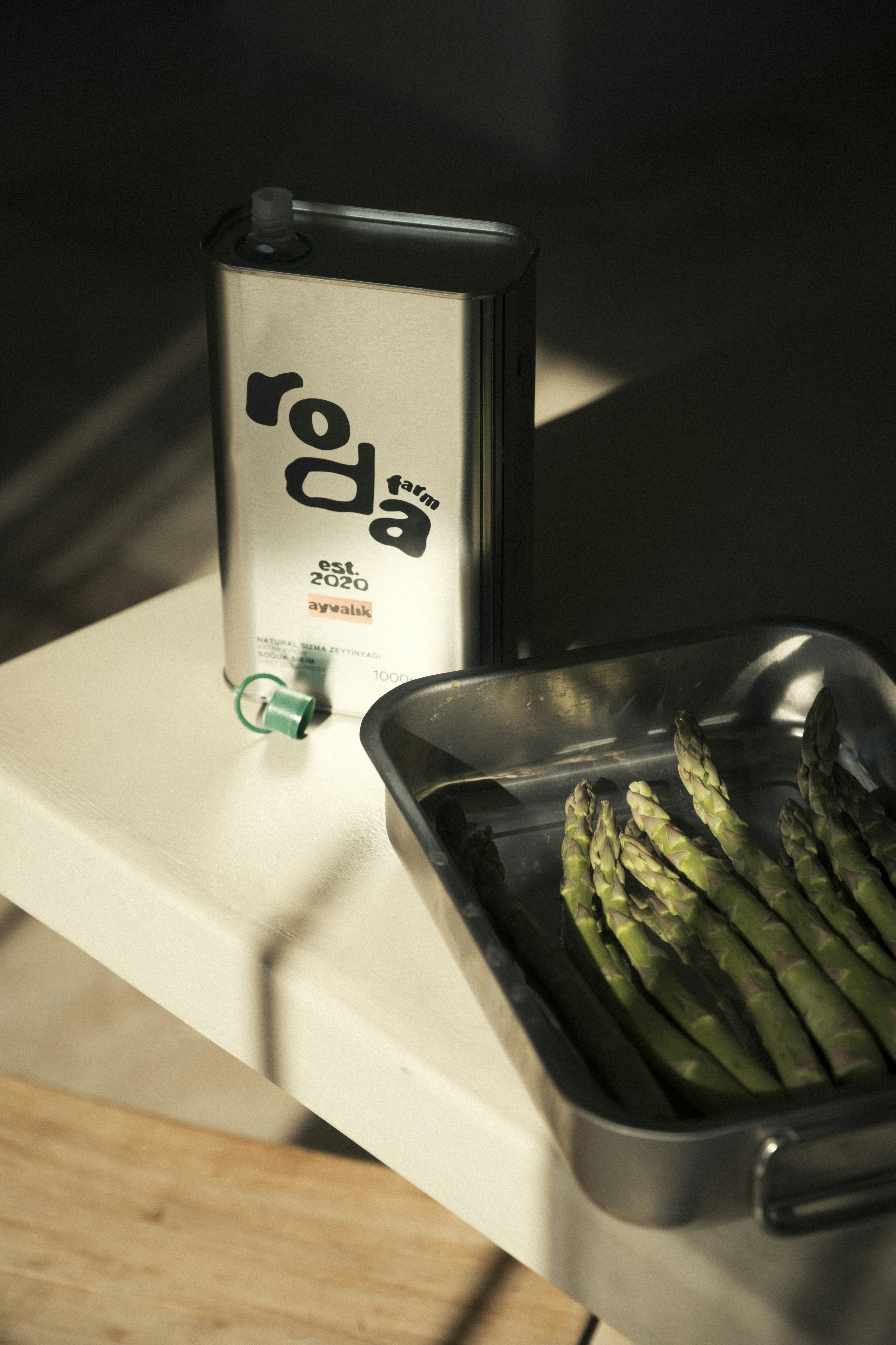 Can of olive oil and asparagus in a pan.
