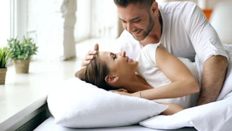 Couple in bed looking at each other lovingly.