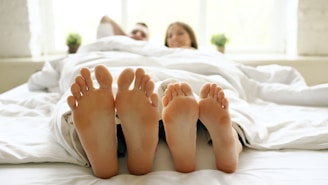 Couple's feet sticking out from under white duvet