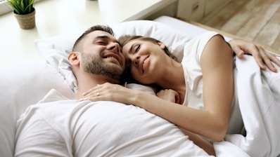 Couple cuddling in bed with eyes closed