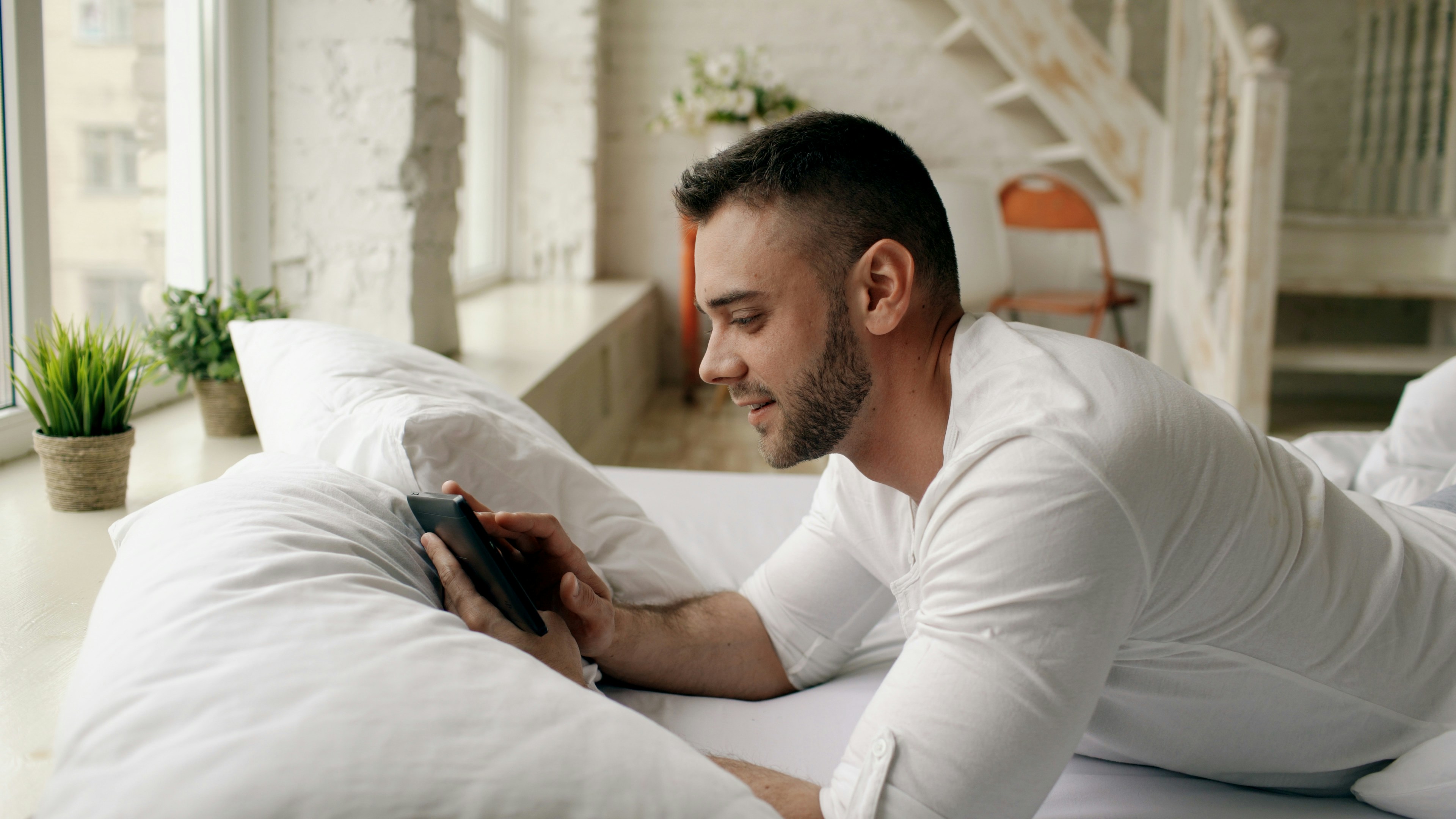 Man lying on bed looking at phone