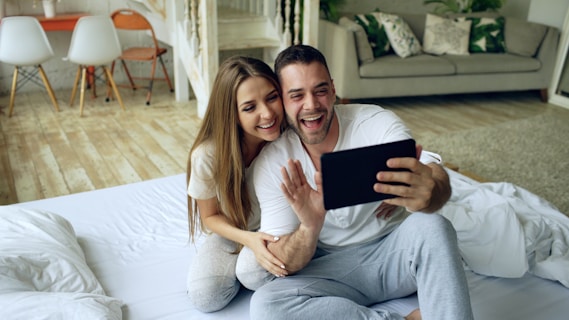 Couple taking a selfie with a tablet in bed.