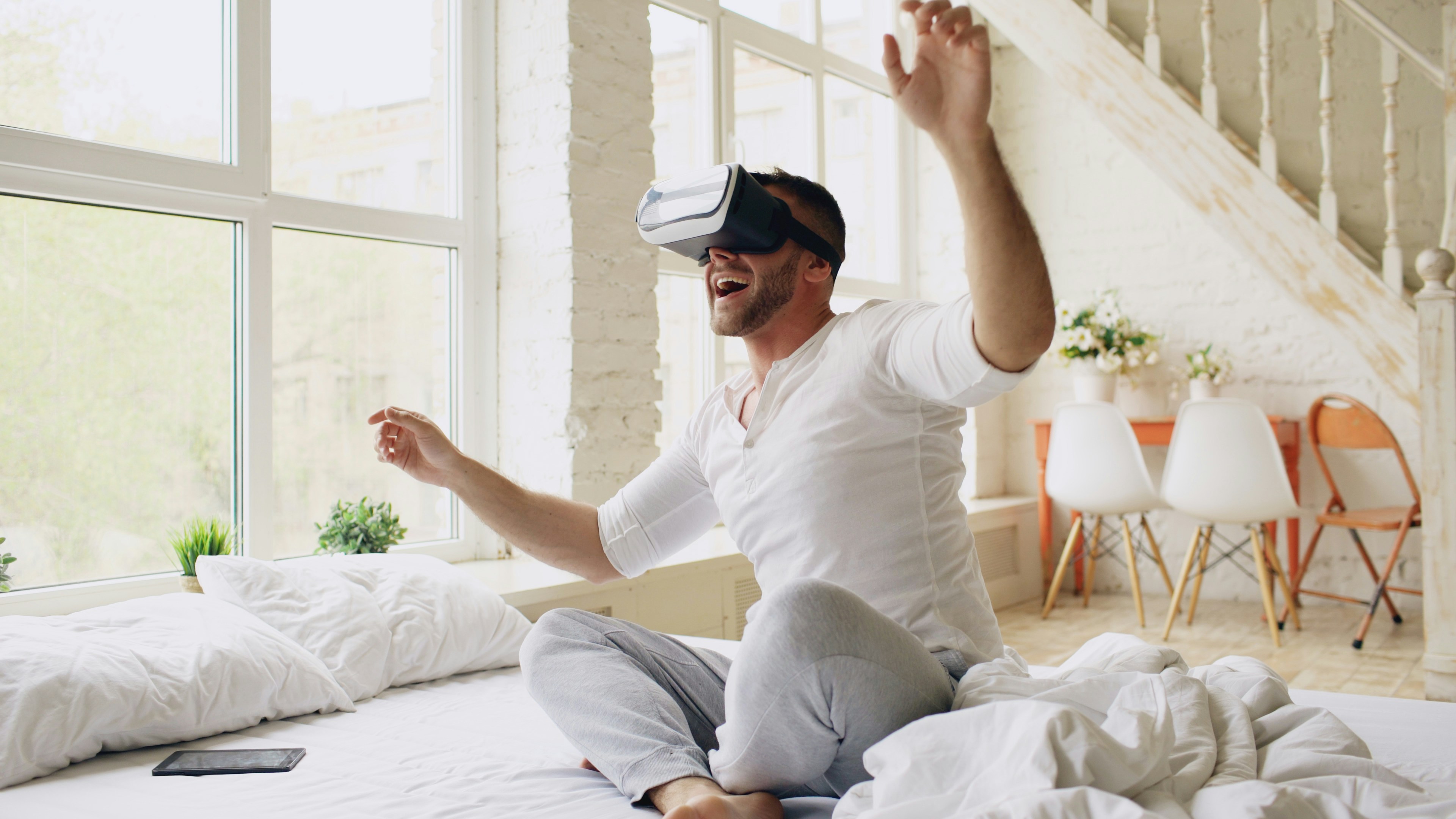 Excited man using VR headset on bed