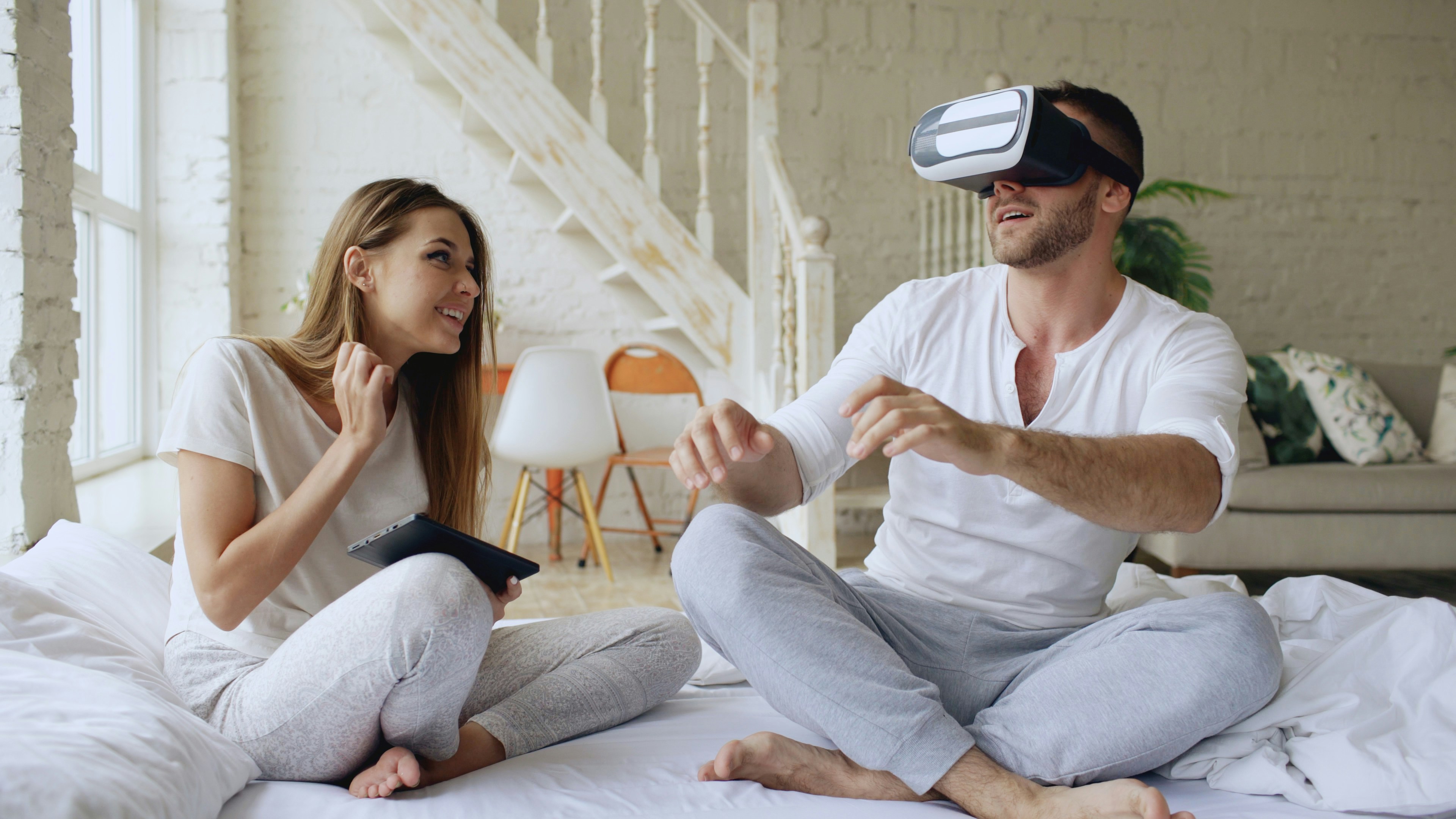 Couple using virtual reality headset in bed