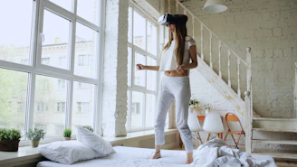 Woman wearing vr headset standing on bed