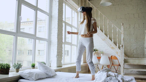 Woman wearing vr headset standing on bed