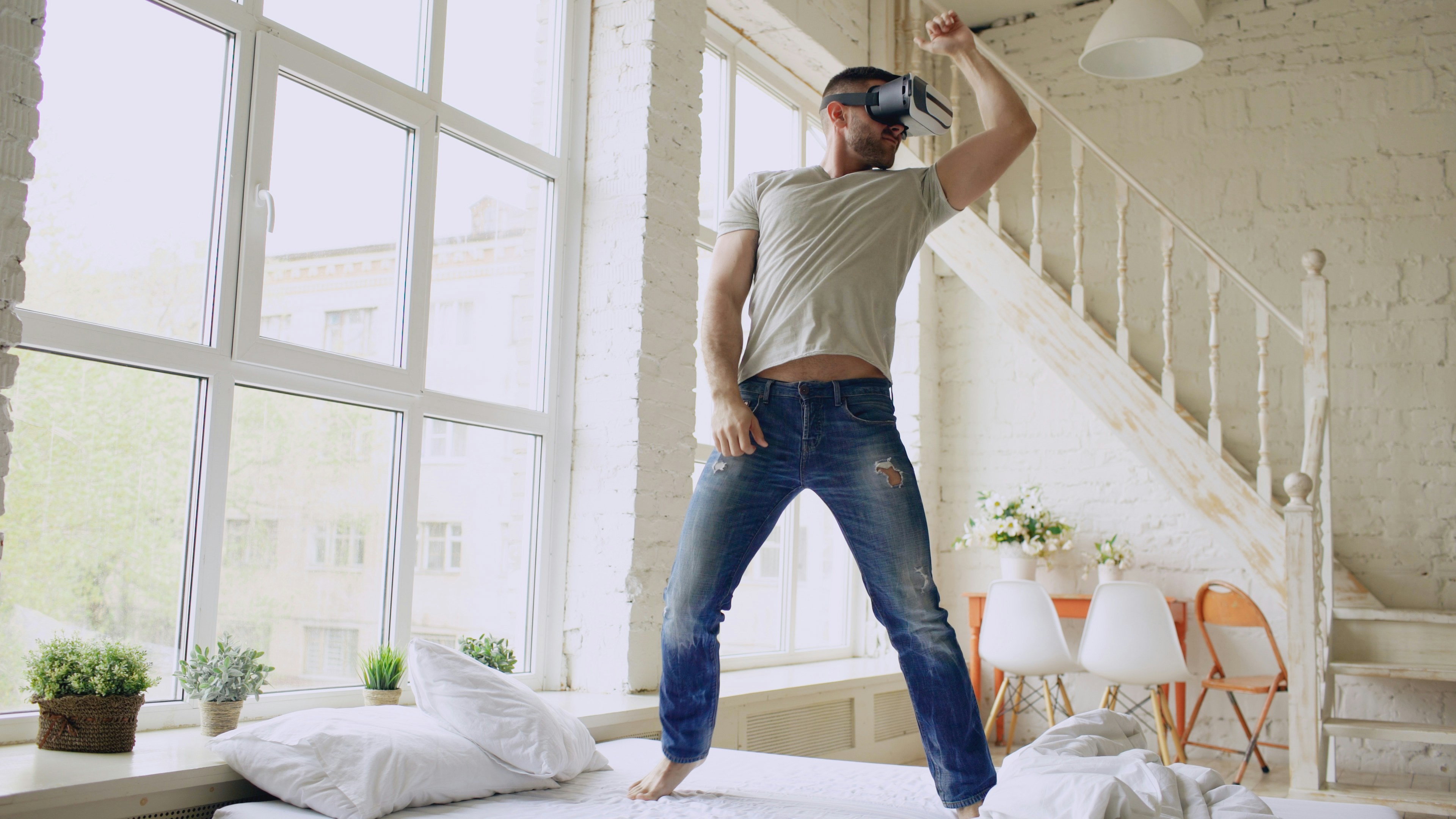 Hombre con auriculares de realidad virtual bailando en una habitación luminosa