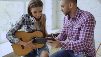 Man and woman learning guitar from phone