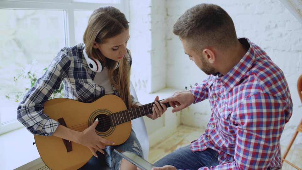 A music instructor teaching a student on the guitar