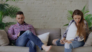 Couple sitting on sofa looking at phones
