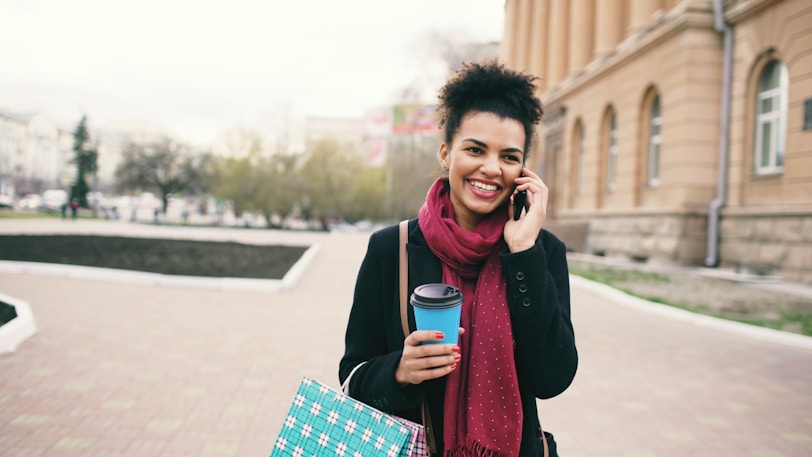 Smiling woman holding coffee cup and talking on phone.
