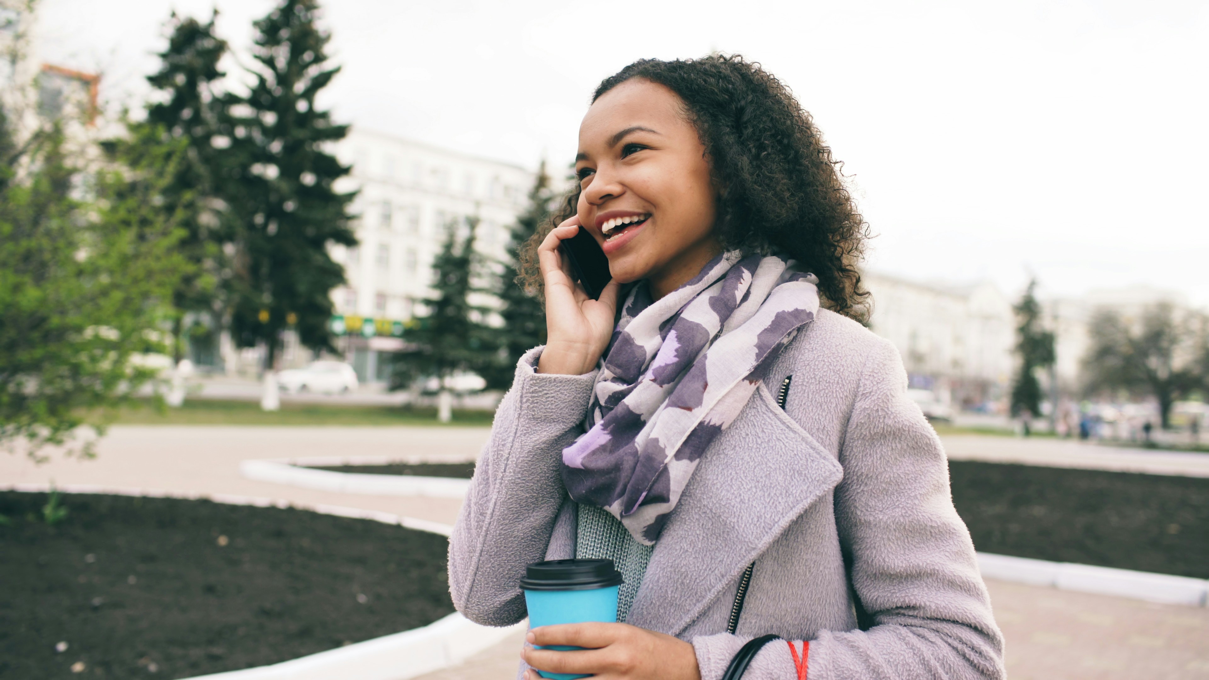 Young woman talking on phone with coffee cup