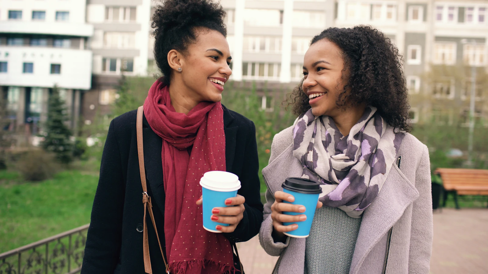 Zwei Frauen spazieren mit Kaffeebechern durch die Stadt