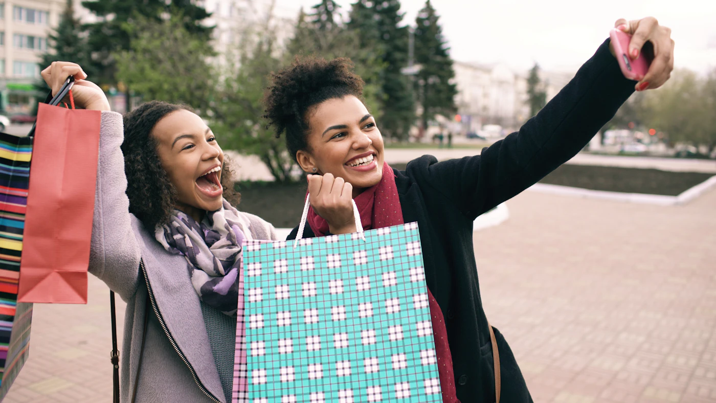 Two happy women taking a selfie with their shopping bags after a purchase