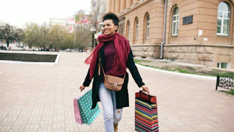 A woman walks with shopping bags and a scarf.