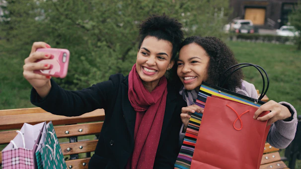 Two smiling women taking a selfie with a smartphone.