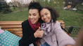 Two smiling women taking a selfie on a park bench.