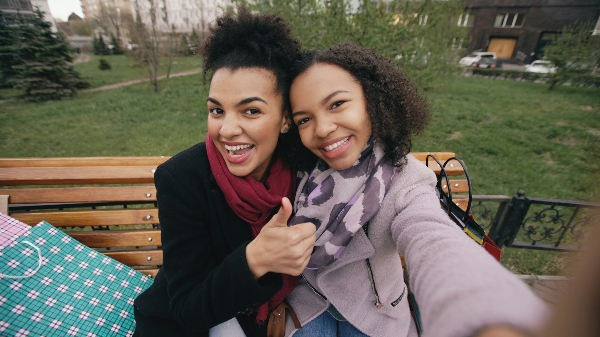 Two smiling women taking a selfie on a park bench.