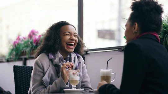 Two women laughing at a cafe table