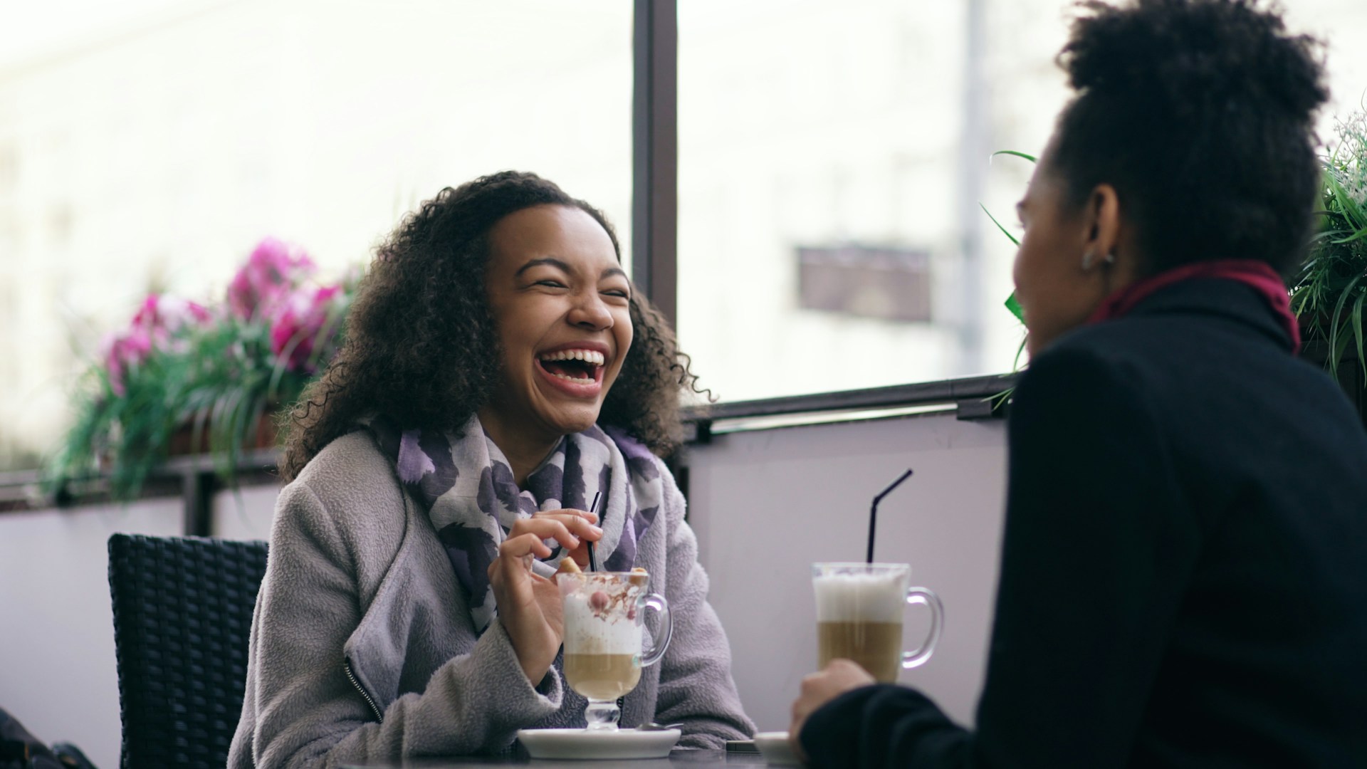 Two women laughing at a cafe table