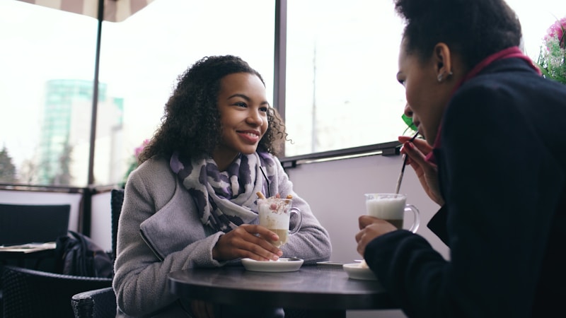 Two women enjoying coffee at an outdoor cafe.